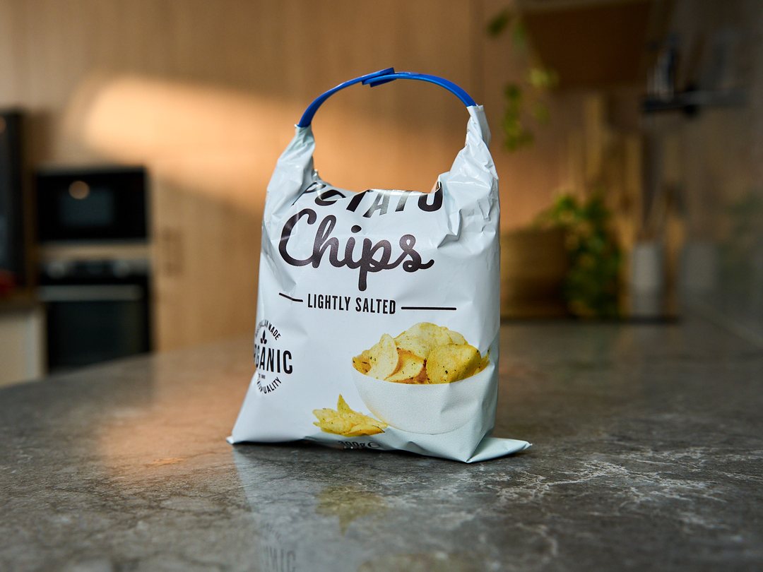 A bag of chips on a kitchen bench, its top rolled down and held with a Blueberry Looplock