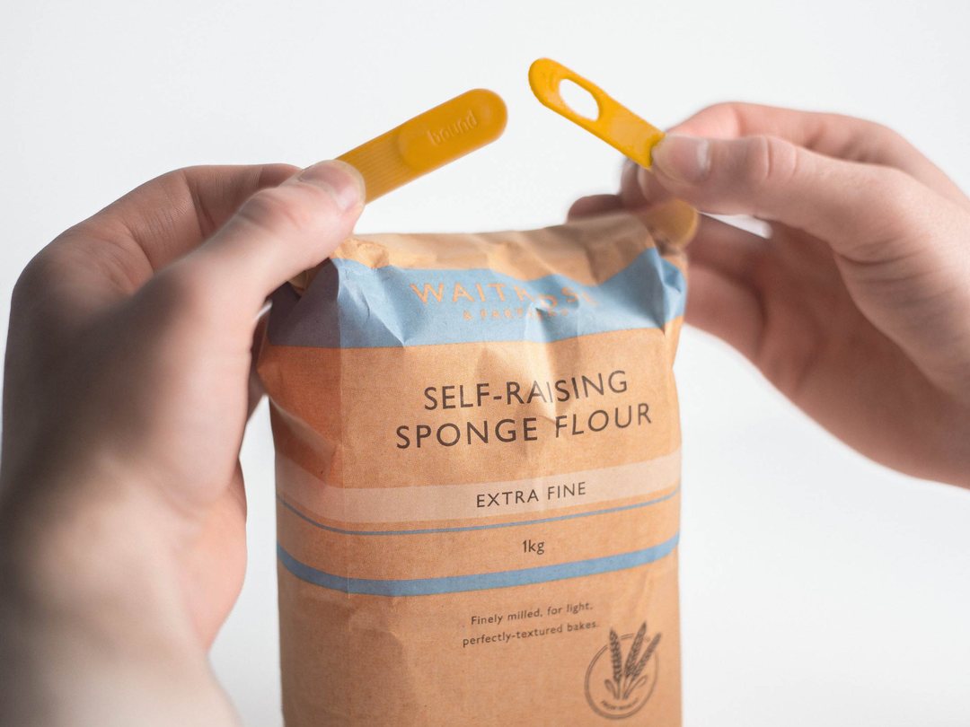 Two hands bringing the ends of a Mango Looplock together over a bag of flour